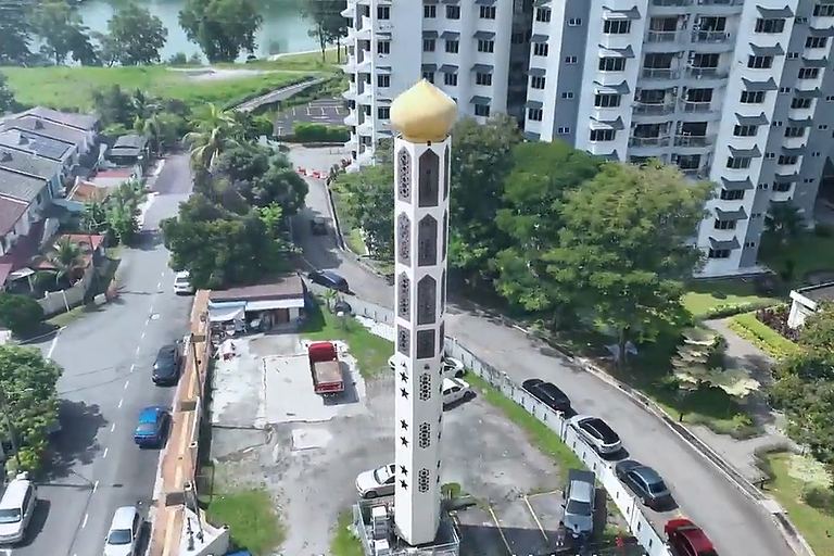 Aerial view of a minaret-style telecommunication structure in a Malaysian neighbourhood