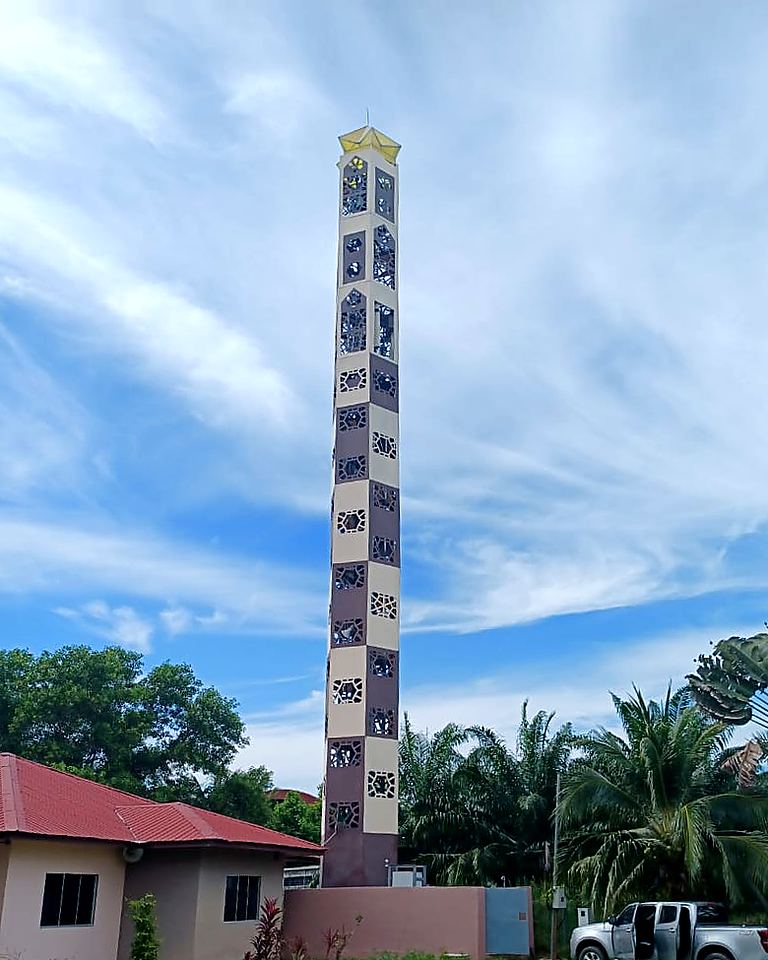Tall minaret-style tower beside a house, under a clear sky
